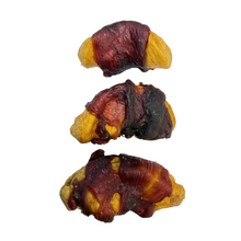 Load image into Gallery viewer, Three Apple Slices Wrapped in Duck Breast Dog Treats. Each item is wrapped in a strip of cured meat, showing varying degrees of browning from light golden-brown to dark charred black.