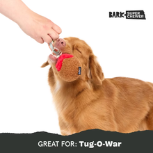 Load image into Gallery viewer, A golden retriever dog is shown biting a plush tug toy while a human hand holds the toy's handle against a white background. The BARK Super Chewer brand logo is visible in the top right, and a dark banner at the bottom reads 'GREAT FOR: Tug-O-War'.