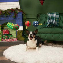 Load image into Gallery viewer, Dog playing with toys in a festive living room with Christmas decorations.