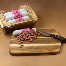 Load image into Gallery viewer, Lamb pate packages on a wooden cutting board with a knife, against a brown background.