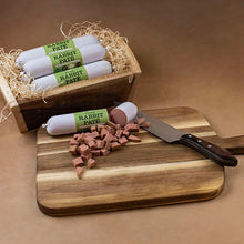 Load image into Gallery viewer, Wooden crate with rabbit pate rolls, a knife, and cut pieces on a cutting board.