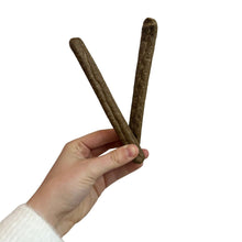Load image into Gallery viewer, Hand holding three brown dog treats against a white background