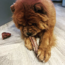 Load image into Gallery viewer, Dog chewing on a rawhide bone on a wooden floor.