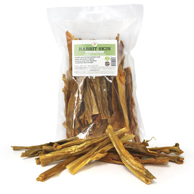 Packaged rabbit skin chews for dogs placed on a white surface, with some chews scattered in front of the package.
