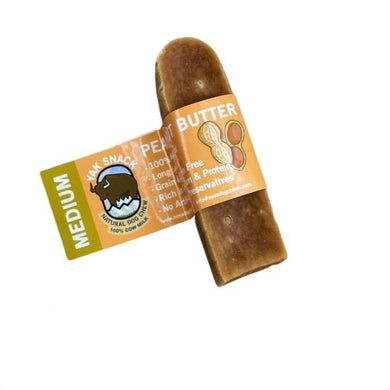 A packaged Nova Yak Snack Peanut Butter Medium, displaying the product through the transparent front of the packaging. The chew is visible, looking like a large, solid, cylindrical object, with a label that includes the product name and a cartoon yak.