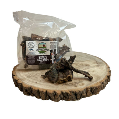A package of Nova Buffalo Steak Strips placed on a wooden disc, with one strip partially out of the package, showing a natural and textured appearance.