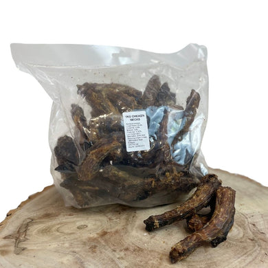 A clear plastic bag containing dried chicken neck pieces on a wooden surface.