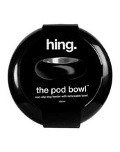 Load image into Gallery viewer, A black circular dog feeder container with a central handle opening, featuring white text that reads ' hing. the pod bowl non-slip dog feeder with removable bowl 300ml'.
