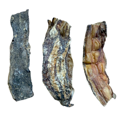 Three crocodile skin chews of varying shapes and colors, intended as dog treats.