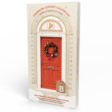 Load image into Gallery viewer, A boxed advent calendar package standing upright on a white studio background. The front shows an illustrated red front door with a holiday wreath, arched doorway details, and red text reading 'PREMIUM ADVENT CALENDAR' and 'for dogs and puppies over 4 weeks.
