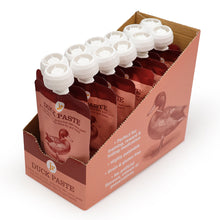 Load image into Gallery viewer, A cardboard display box holding multiple pouches of duck paste training medication. The pouches are dark reddish-brown with white caps and printed duck illustrations, arranged inside a peach-colored box with product text and a duck graphic.
