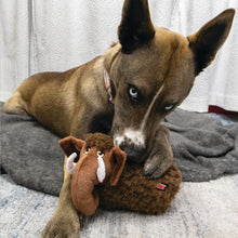 Load image into Gallery viewer, Dog lying on a bed with a plush toy resembling a dog's face.
