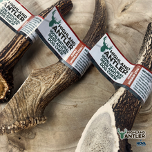 Load image into Gallery viewer, Deer antlers with Highland Antler labels on a wooden surface
